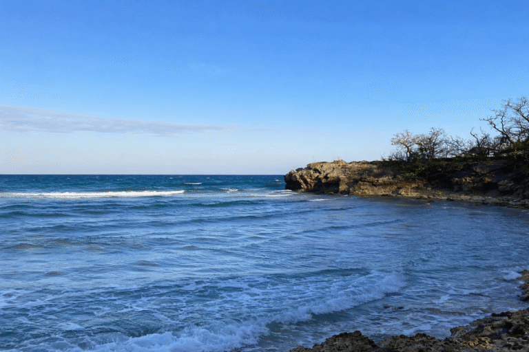 Pemandangan Pantai Kahuripan Gili Genting dengan garis pantai berbatu, tebing alami, dan langit biru terbuka.